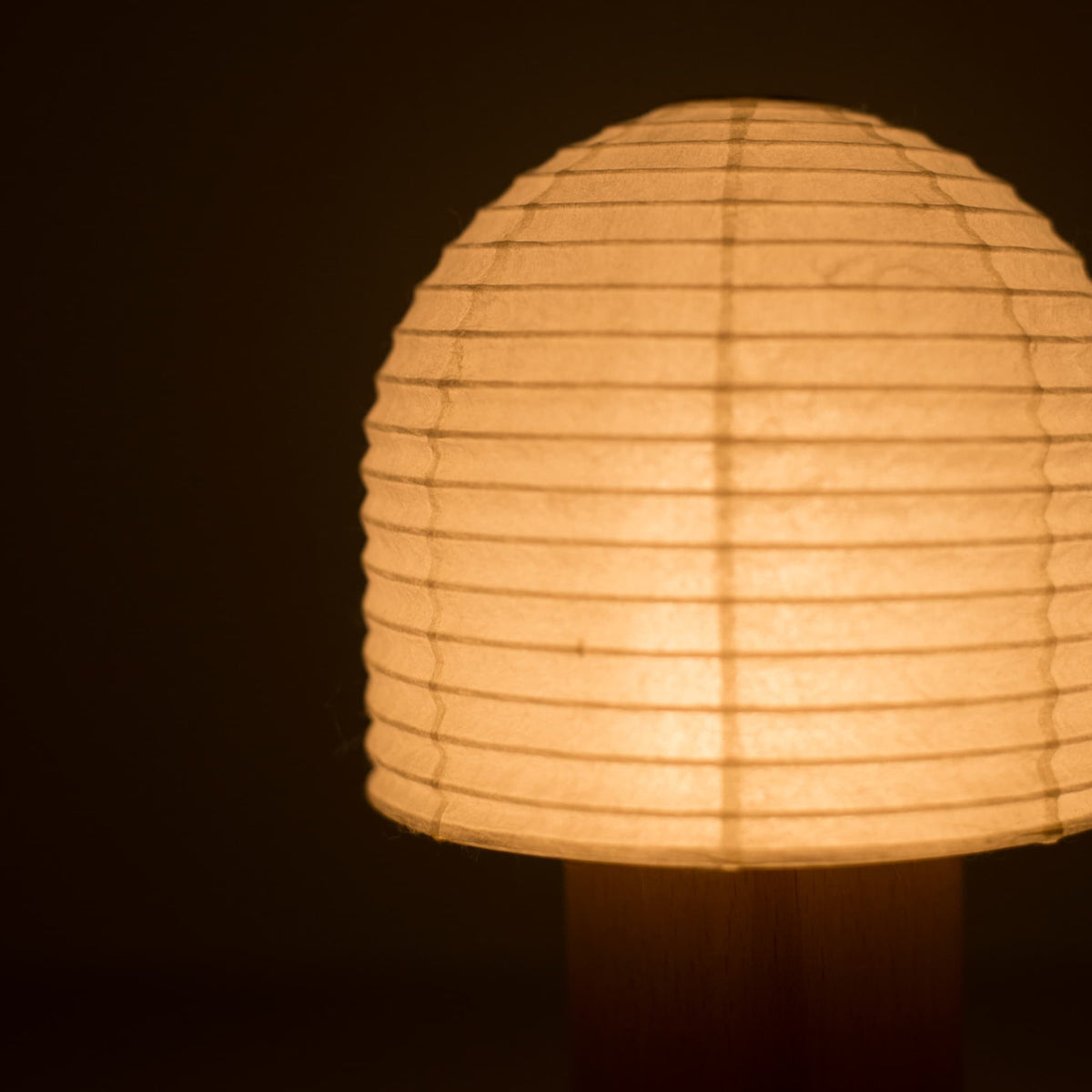 Gezicht van een belvormige Yame-lantaarn die warm licht uitstraalt in een donkere kamer