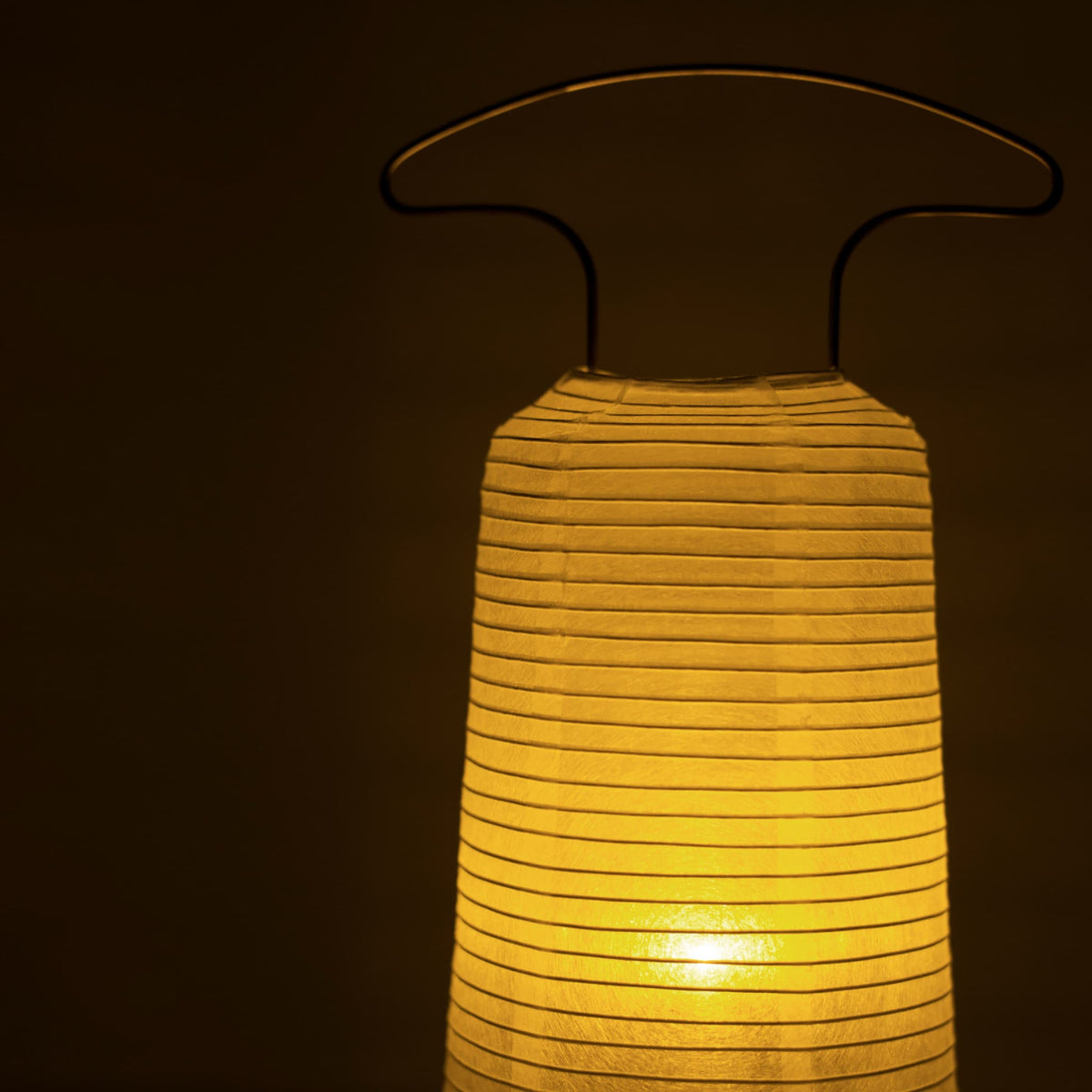 Close-up van een traditionele Japanse papieren lantaarn die warm licht uitstraalt in een donkere kamer