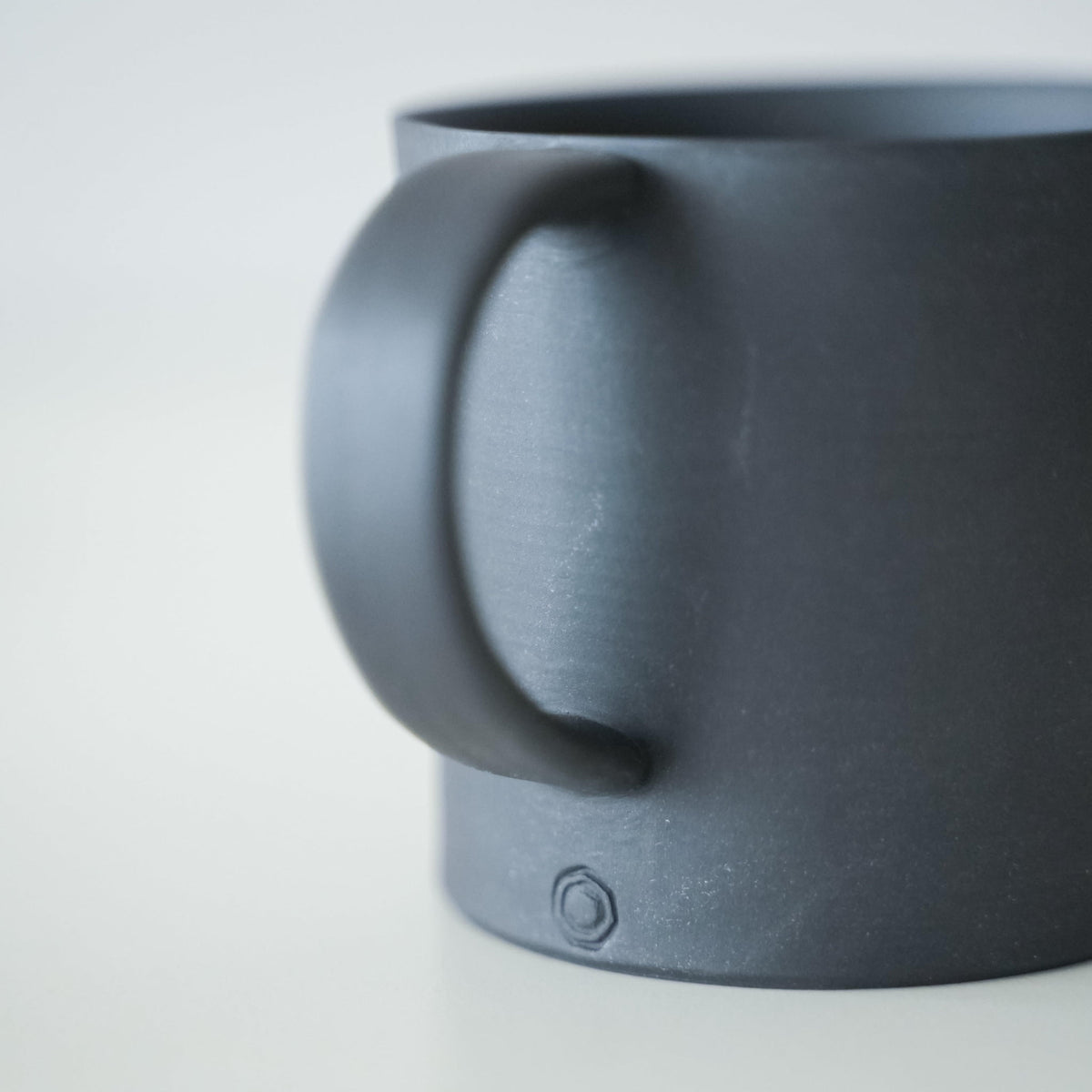 Der Henkel einer schlichten schwarzen Banko-Keramik-Tasse.