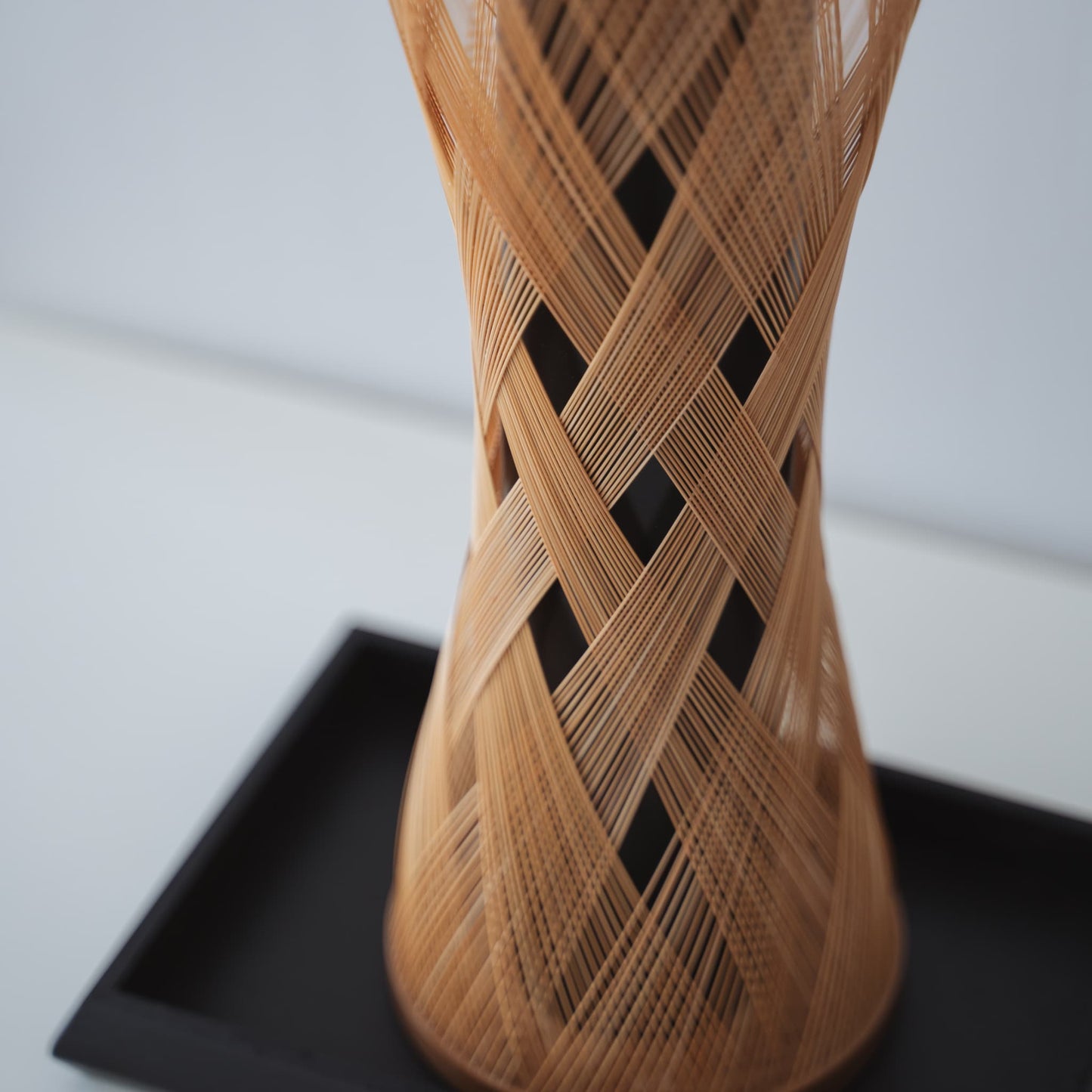 Eine japanische Bambus-Ikebana-Vase auf einem weißen Tisch