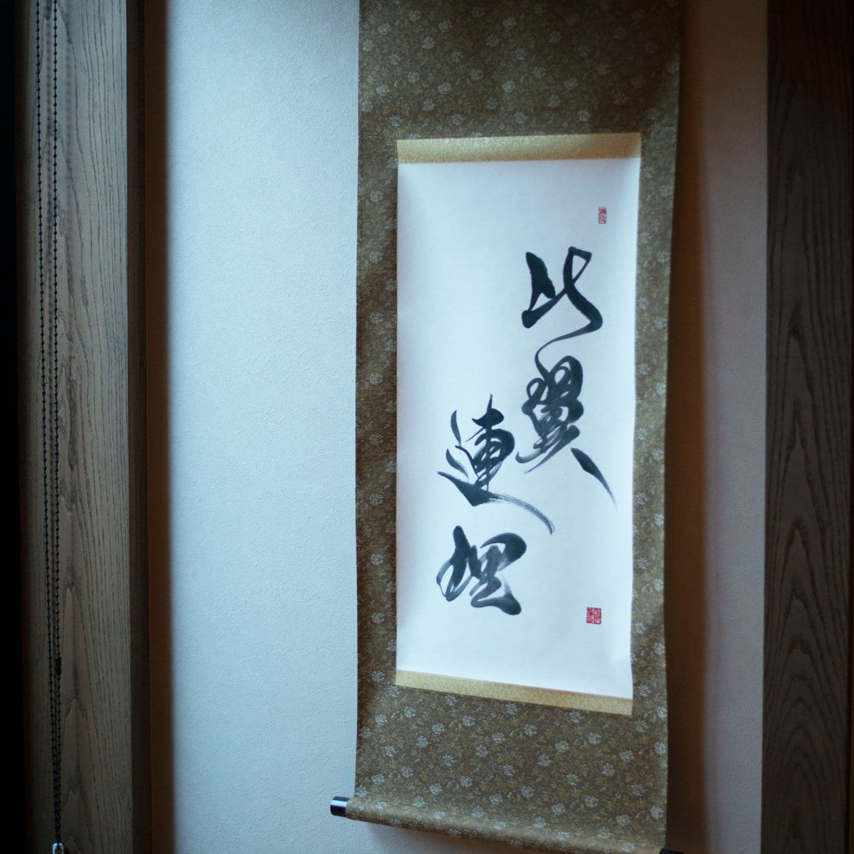 Japanese calligraphy scroll in tokonoma alcove with Hiyoku Renri inscription, angled view