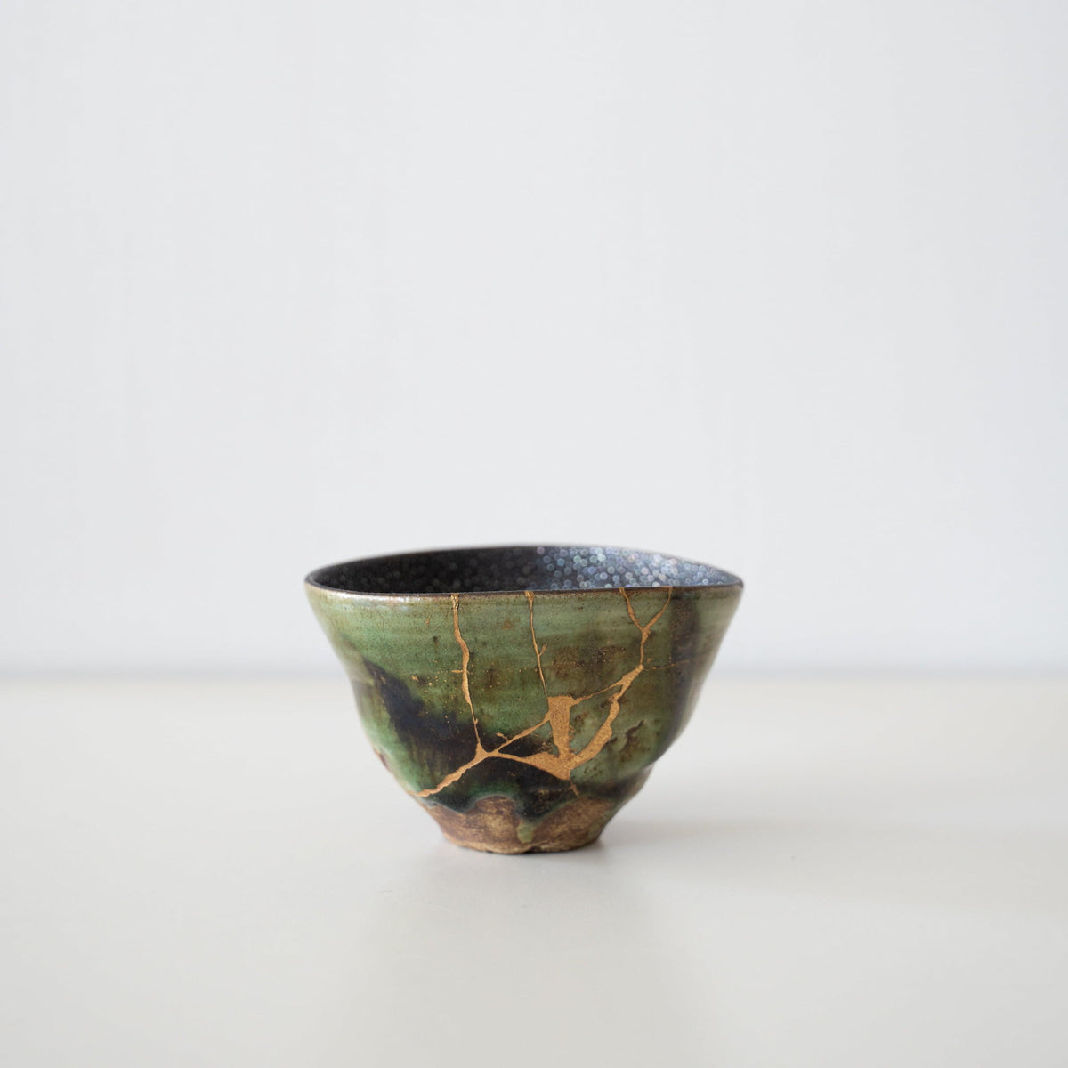 Diepgroene theekom, gerepareerd met Kintsugi, een traditionele Japanse techniek die de schoonheid van imperfectie toont.