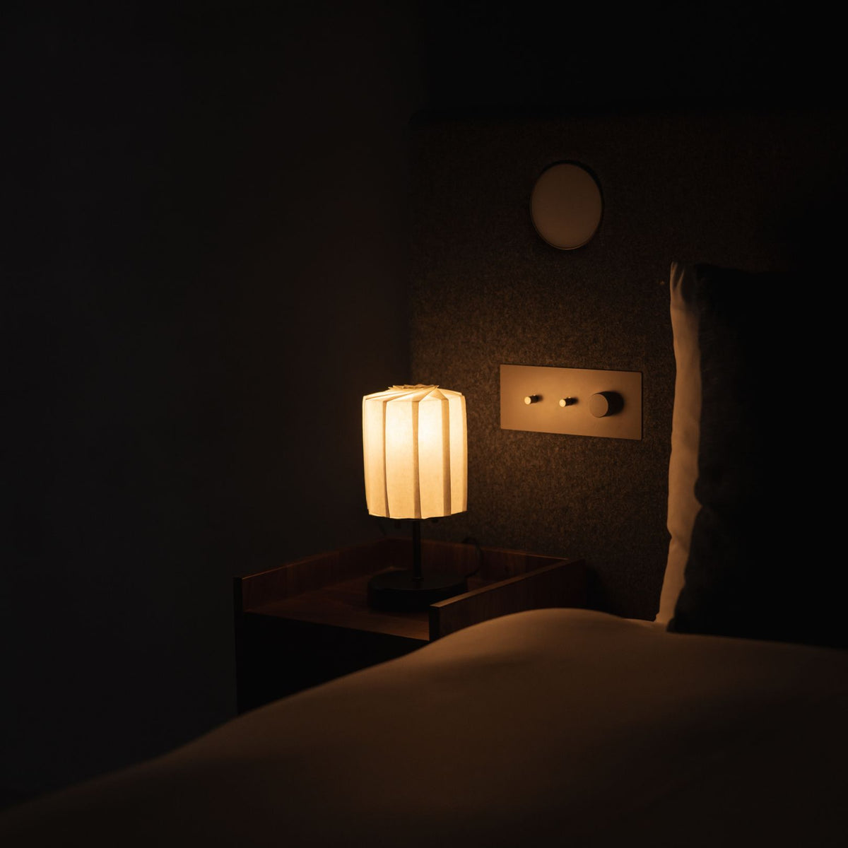"Lampe de table japonaise en papier « Fleur de lumière tutu avec support » allumée sur une table de chevet en bois"