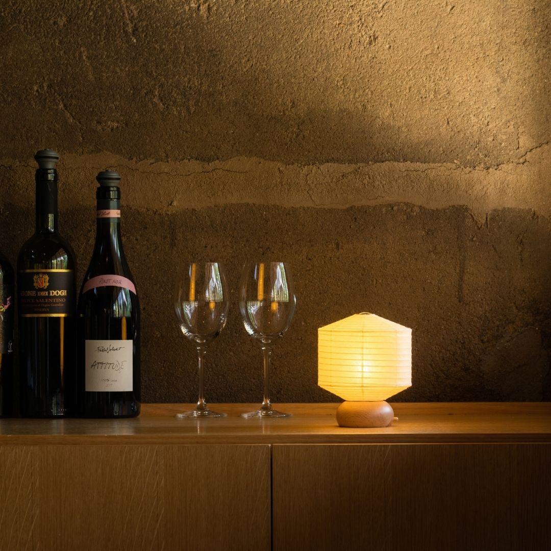 Japanese Paper Table Lamp "Mini Square" with wine bottles and wine glasses on a wood shelf on corner in a room