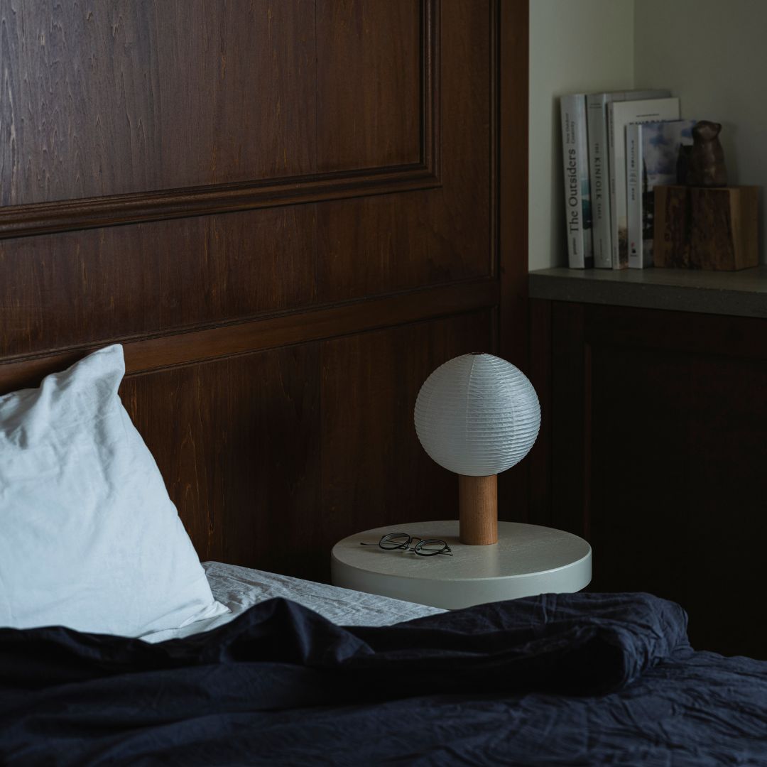 "Een slaapkamer met een bed aan de linkerkant en een boekenplank met boeken aan de rechterkant. Op het nachtkastje rechts van het bed staat een nachtlampje \"TORCHIN\" gemaakt van Japanse Yame-chochin lantaarns."