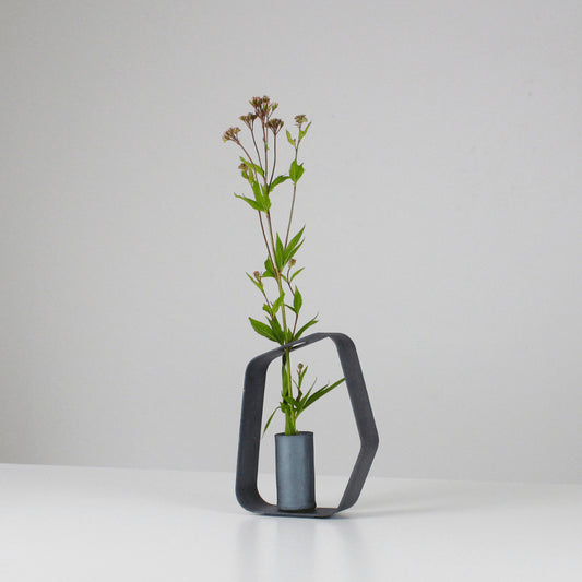 A minimalist black iron vase crafted using traditional Japanese roof tile making techniques, paired with a black wood frame.