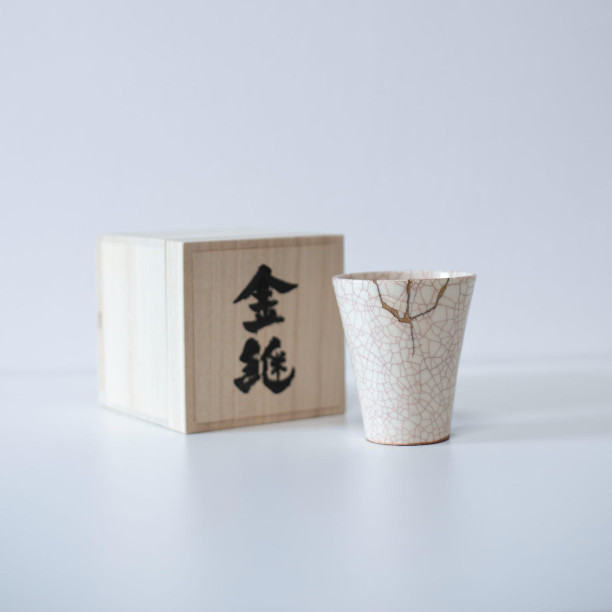 Kintsugi repaired white cup and paulownia wood box gift set, symbolizing the Japanese aesthetic of finding beauty in imperfection.