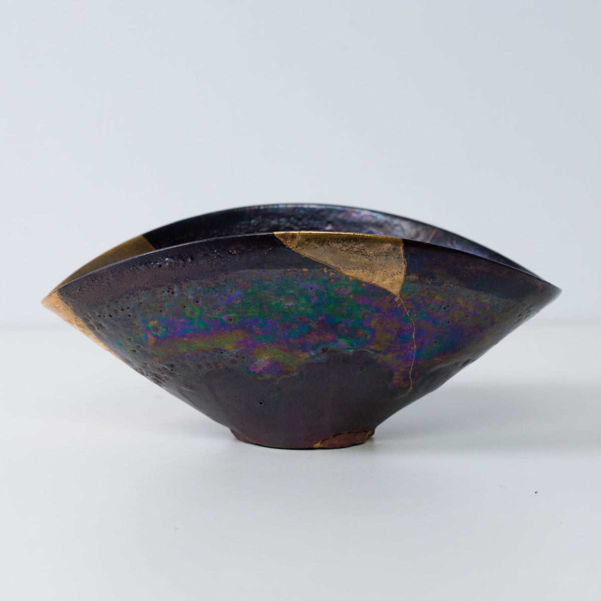 Seitenansicht einer Kintsugi-Keramikschale mit schillernder Glasur und goldenen Kintsugi-Nähten