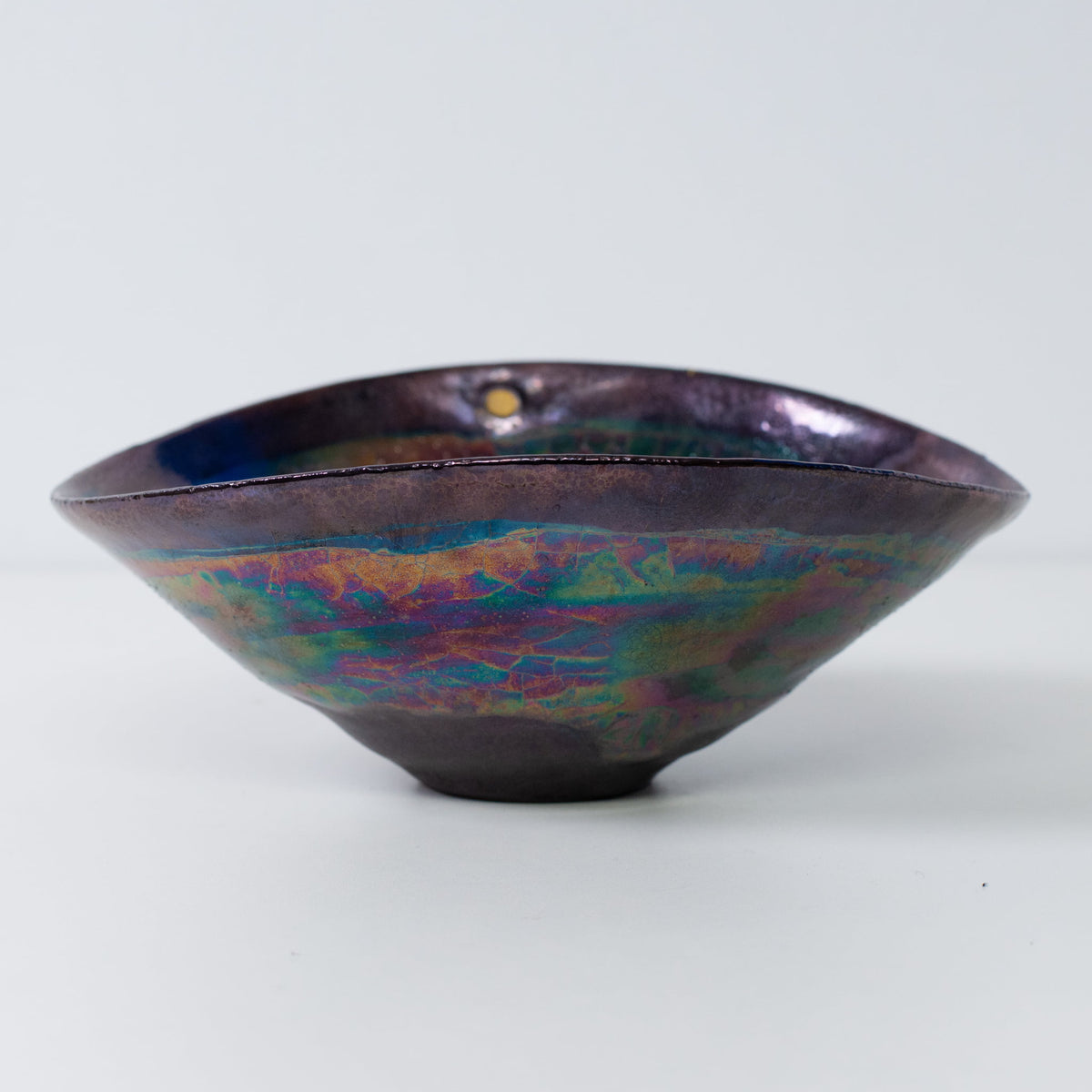 Japanese Kintsugi pottery bowl side view with metallic glaze and gold-filled cracks
