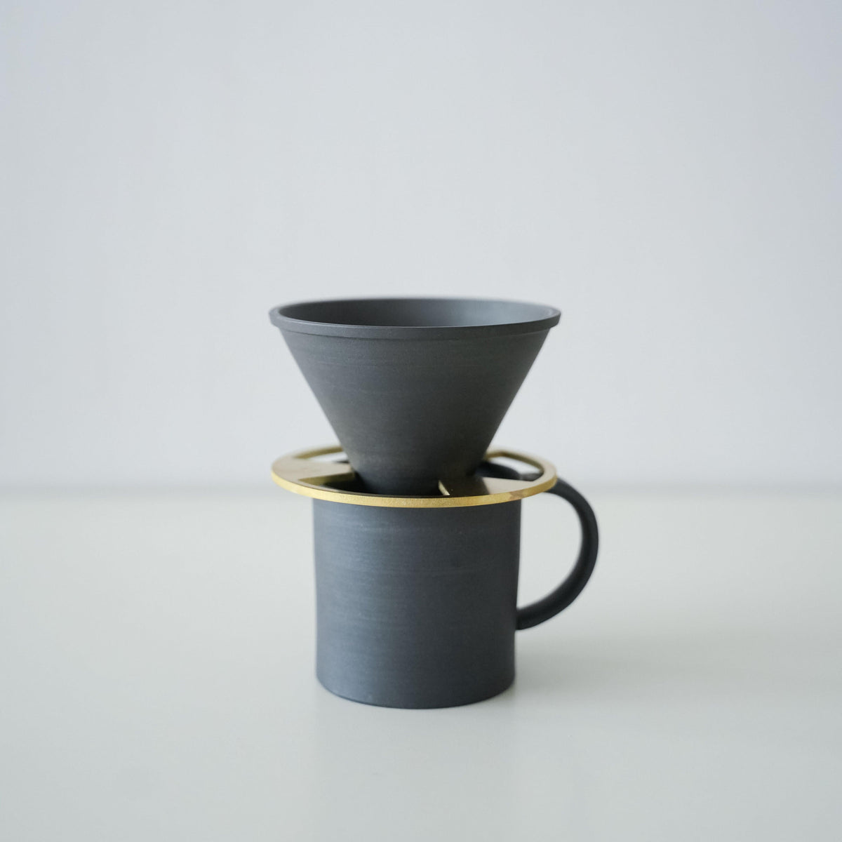Ein minimalistischer schwarzer Kaffeebecher und ein Kaffee-Dripper