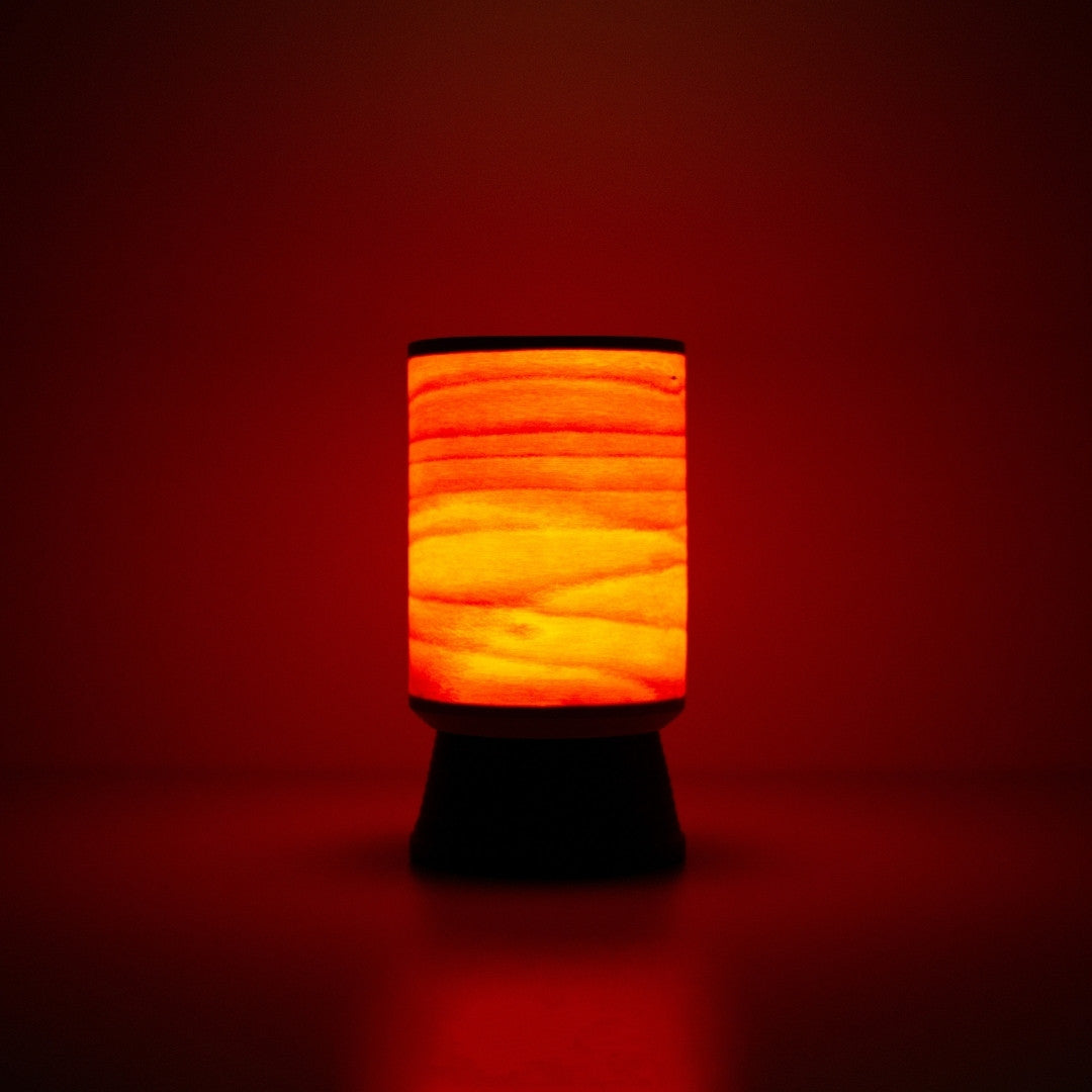 Lampe japonaise en bois avec une lueur rougeâtre chaleureuse à travers un abat-jour en hêtre, parfaite pour les intérieurs douillets.