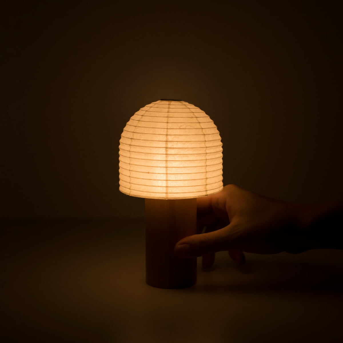 Een hand die een warm gloeiende Yame-lantaarn vasthoudt in een donkere kamer