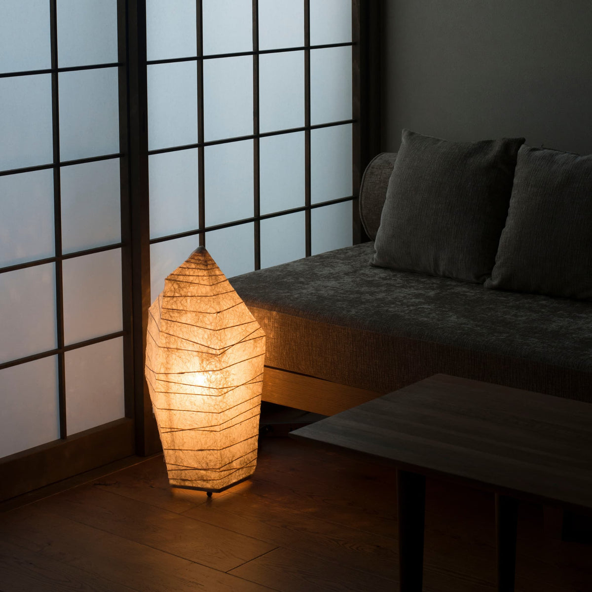 Japansk papir gulvlampe med isstensdesign, der udsender varmt lys, fanget fra en vinkel ovenfra i et traditionelt japansk rum.