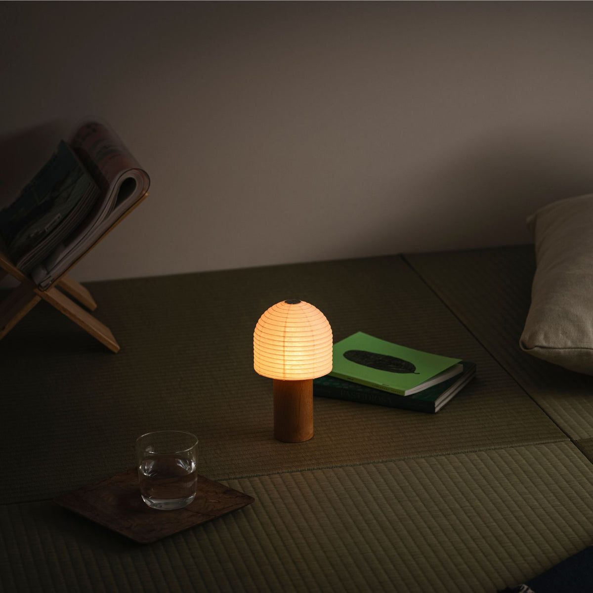Een draagbare Yame-lantaarn die warm gloeit, geplaatst op een traditionele tatamimat in een kamer in Japanse stijl