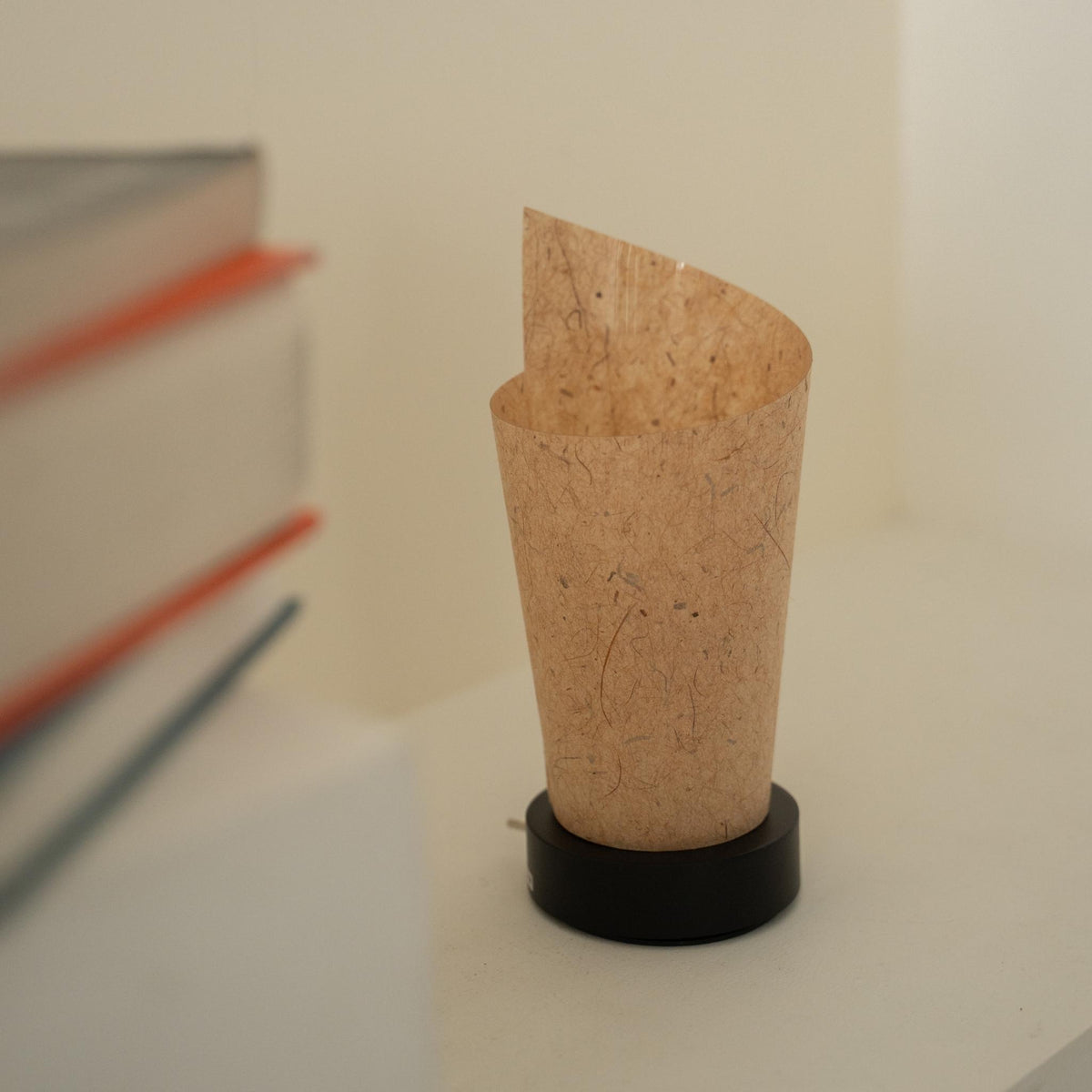 Nærbillede af en utændt japansk papir bordlampe "Maki" cedertræsbark, der viser dens rullede design og naturlige papirtekstur til wabi sabi indretning.