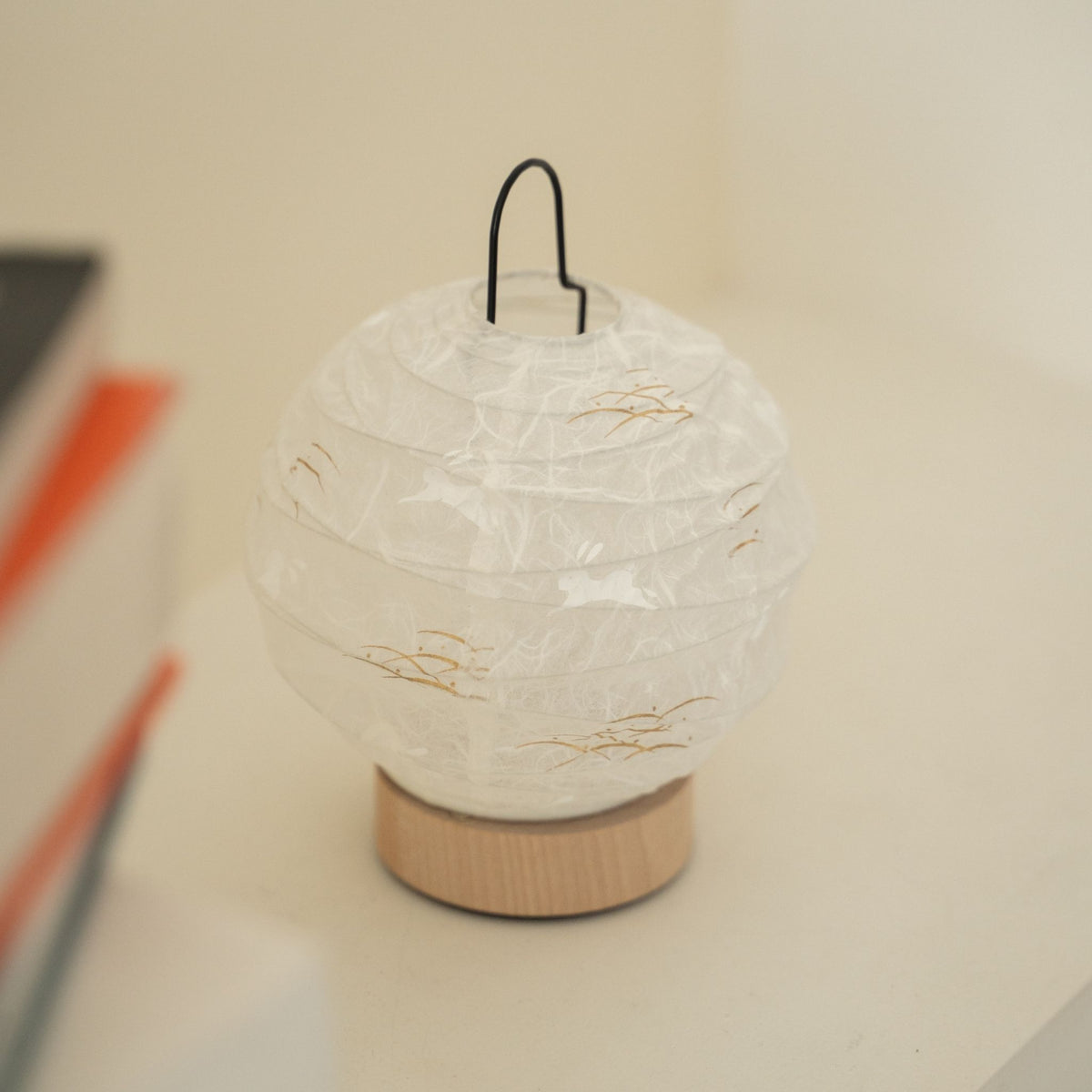 Close-up of an unlit round Japanese paper table lamp "Yuhi" Rabbit showcasing its textured paper surface for wabi sabi decor on a Japandi living room console table.
