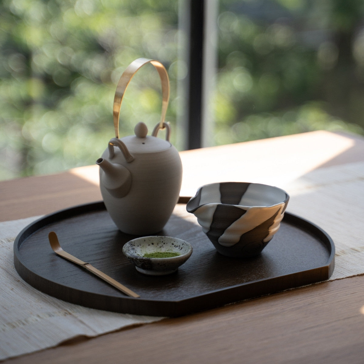 Bol à matcha japonais blanc Flow avec bec verseur et théière sur un plateau en bois près d'une fenêtre, pour une authentique routine de latte au matcha