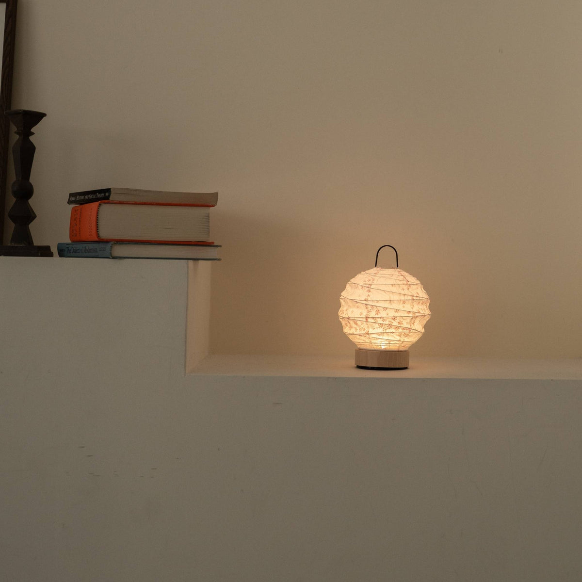 Lit round Japanese paper table lamp "Yuhi" Sakura casting a soft glow as an ambient lamp on a white Japandi style console.