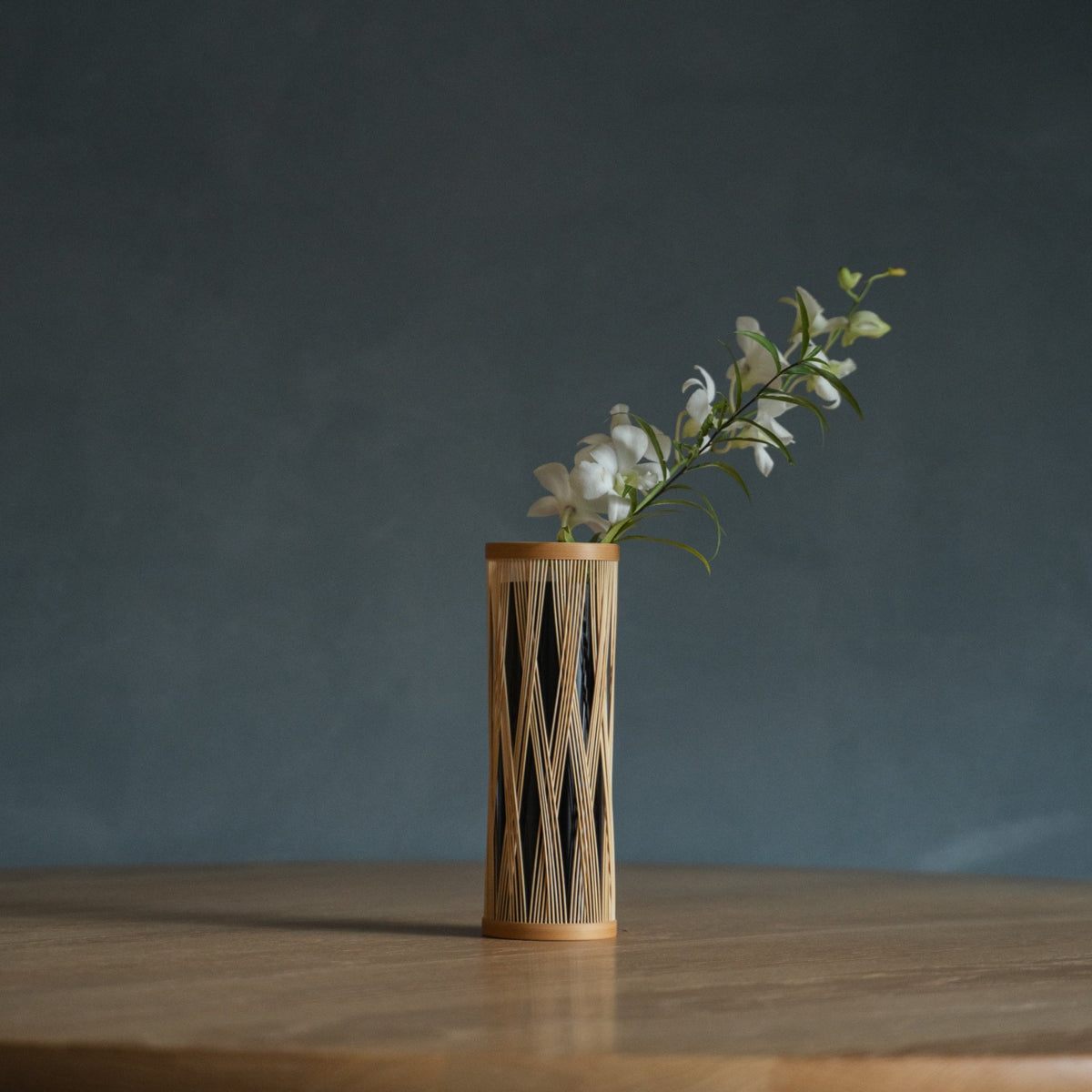 Vase à fleurs en bambou japonais « Branche entrelacée » marron, mis en scène dans un intérieur.