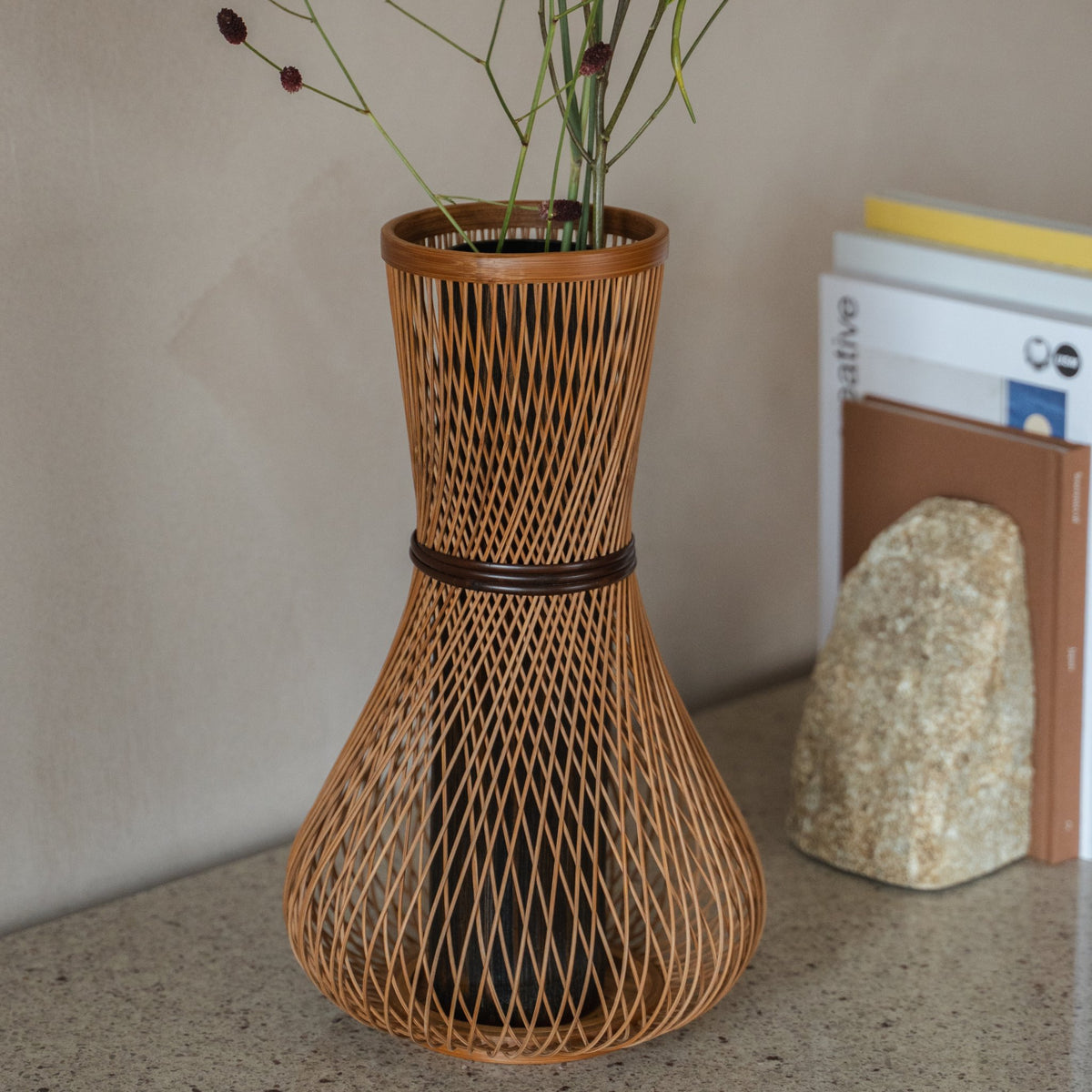 Vase à fleurs en bambou japonais « Fukuju » marron présenté sur une console, vue de la scène.