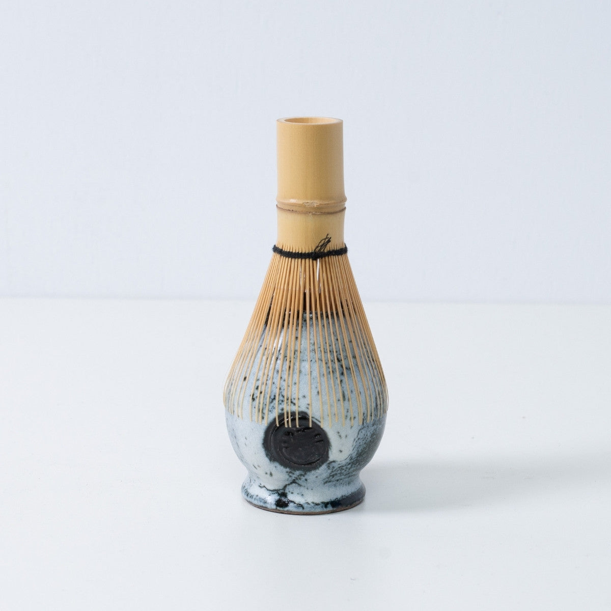 Support en céramique blanc et noir pour fouet à matcha japonais "Creative Cloud", avec un fouet à thé en bambou posé dessus, fabriqué au Japon.
