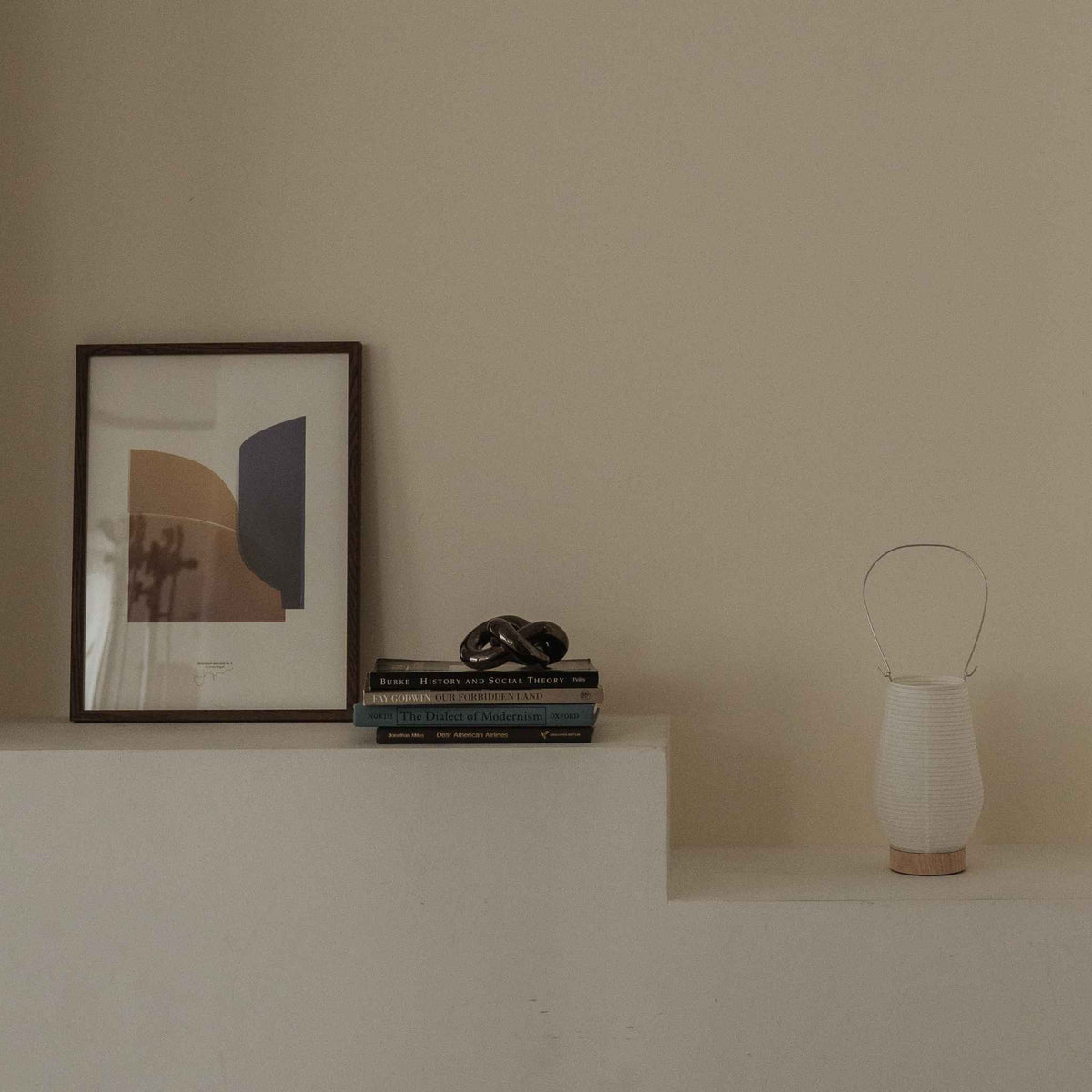 Uden lys japansk papir bordlampe RIN 02 placeret på en hvid hylde ved siden af bøger og kunst i et japandi-stil rum