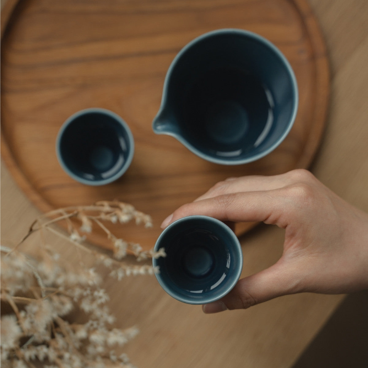 Matte blaue Arita-Porzellan-Guinomi auf einem Holztablett, die Sake-Liebhaber auf ein ruhiges Sake-Ritual am Abend vorbereitet.