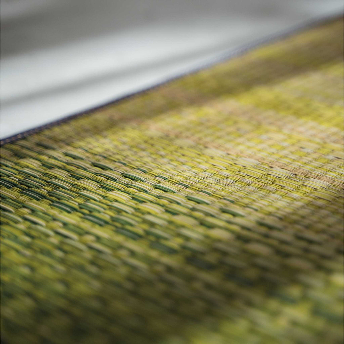 Nahaufnahme der Textur aus gewebtem Schilfgras auf einer grünen Tatami-Matte, die ihre atmungsaktive natürliche Oberfläche zeigt.