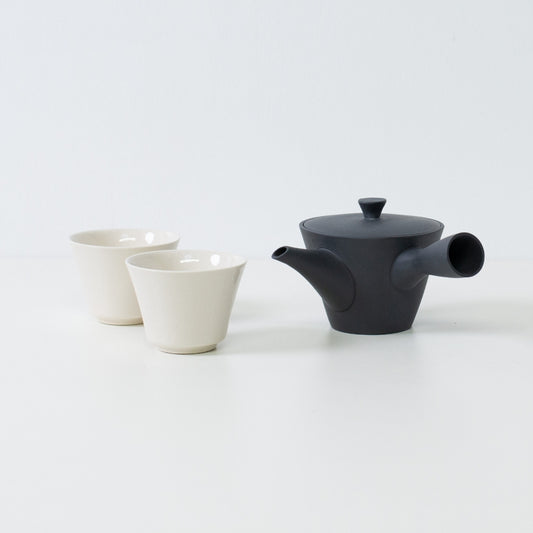 Japanese tea set displaying a black kyusu teapot beside two white crackle glazed kodai tea cups for guest hospitality.