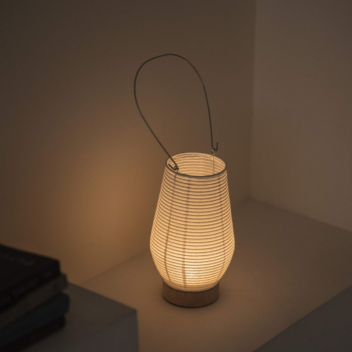 Overheadsbillede af en tændt bærbar lampe lavet af mino washi-papir, der fremhæver den ribbede struktur og det varme lys