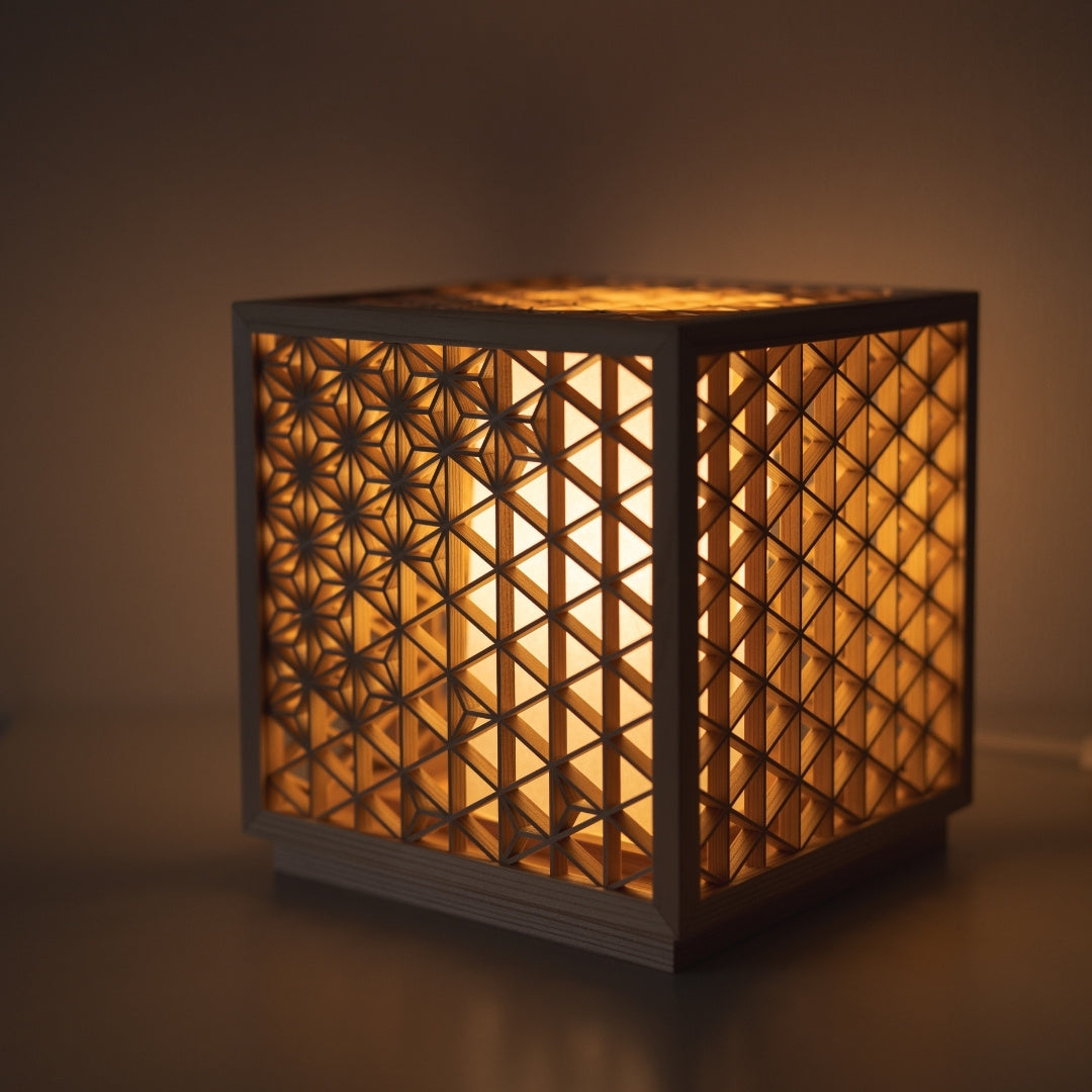 Japanese lamp meticulously handcrafted using the 1400-year-old "kumiko" technique, assembling 600 pieces of premium Akita cedar into a mesmerizing cubic form.
