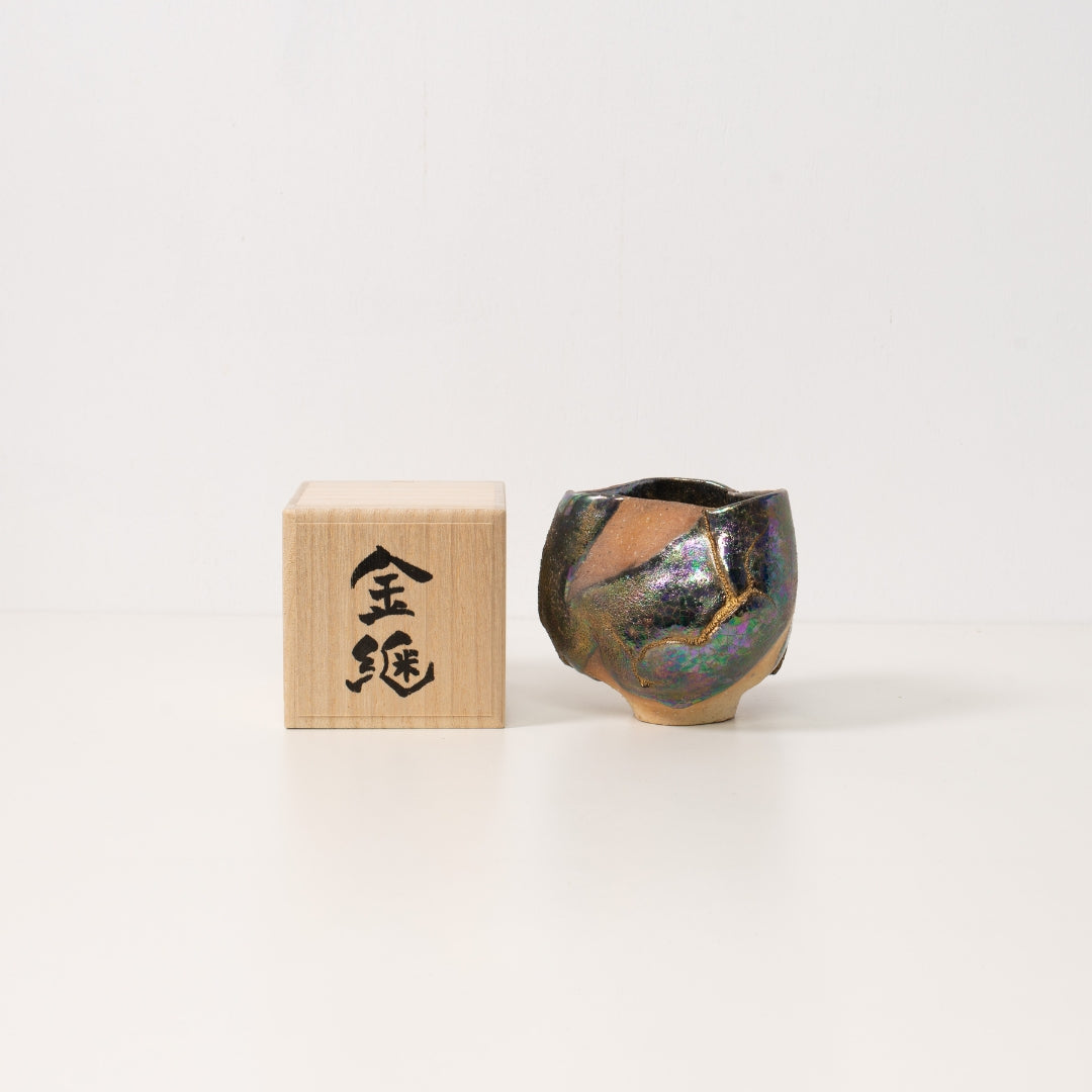"Eine breitere schillernde Kintsugi-Matcha-Schale liegt neben einer Holzbox, bereit als einzigartiges japanisches Geschenk überreicht zu werden"