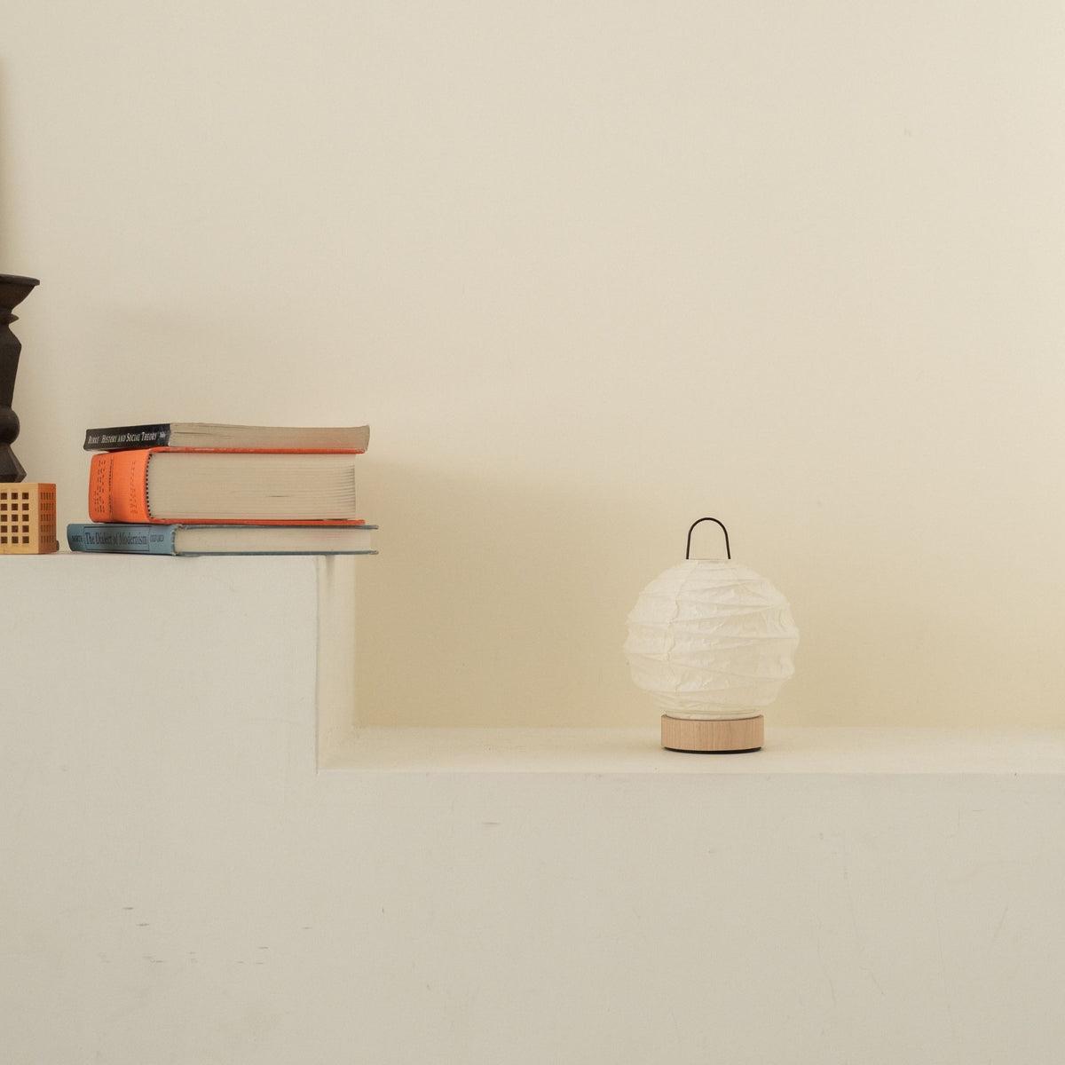 Unlit round Japanese paper table lamp "Yuhi" placed on a white console table in a minimalist Japandi living room.