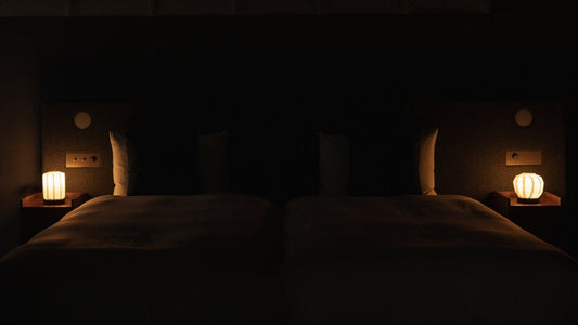 Japanische Papier-Tischlampe "Blume des Lichts M" auf einem Nachttisch aus Holz