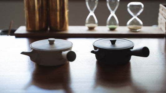 Théière Sencha japonaise artisanale noire et blanche sur une table en bois dans une pièce zen