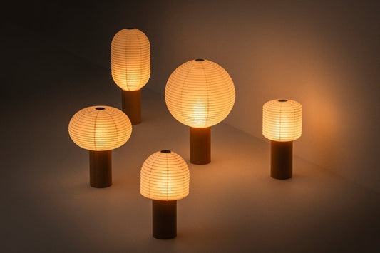 "Lampe japonaise en papier de la série « TORCHIN » diffusant une lumière chaude dans une pièce tamisée"
