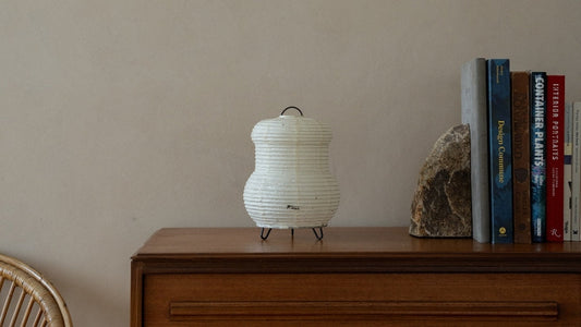 "Japanische Papier Stehlampe \"PAPERSON 03\" auf einem Holztisch in einem Japandi-Zimmer – Wabi-Sabi Papier Nachttischlampe für Schlafzimmer"