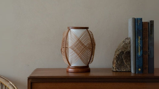 Japanische Bambusregal-Lampe "Koyou" auf einem Holztisch in einem Japandi-Wohnzimmer
