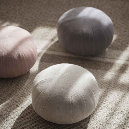 Tre zafu meditationspuder i farverne misty rose, hvidgrå og lagoon gray arrangeret på et tæppe med sollys og skygger.