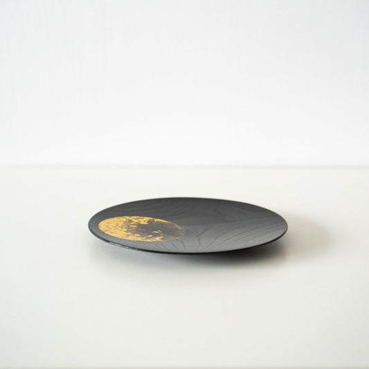 Petite assiette japonaise en laque feuille d'or sur une table blanche