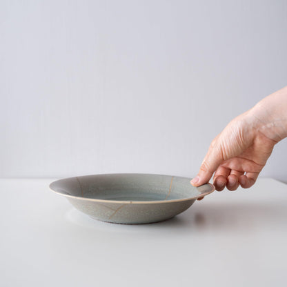 Hånd, der holder Kintsugi-skål "Four Color Yohenyu", viser dens størrelse og hvordan den passer i hånden