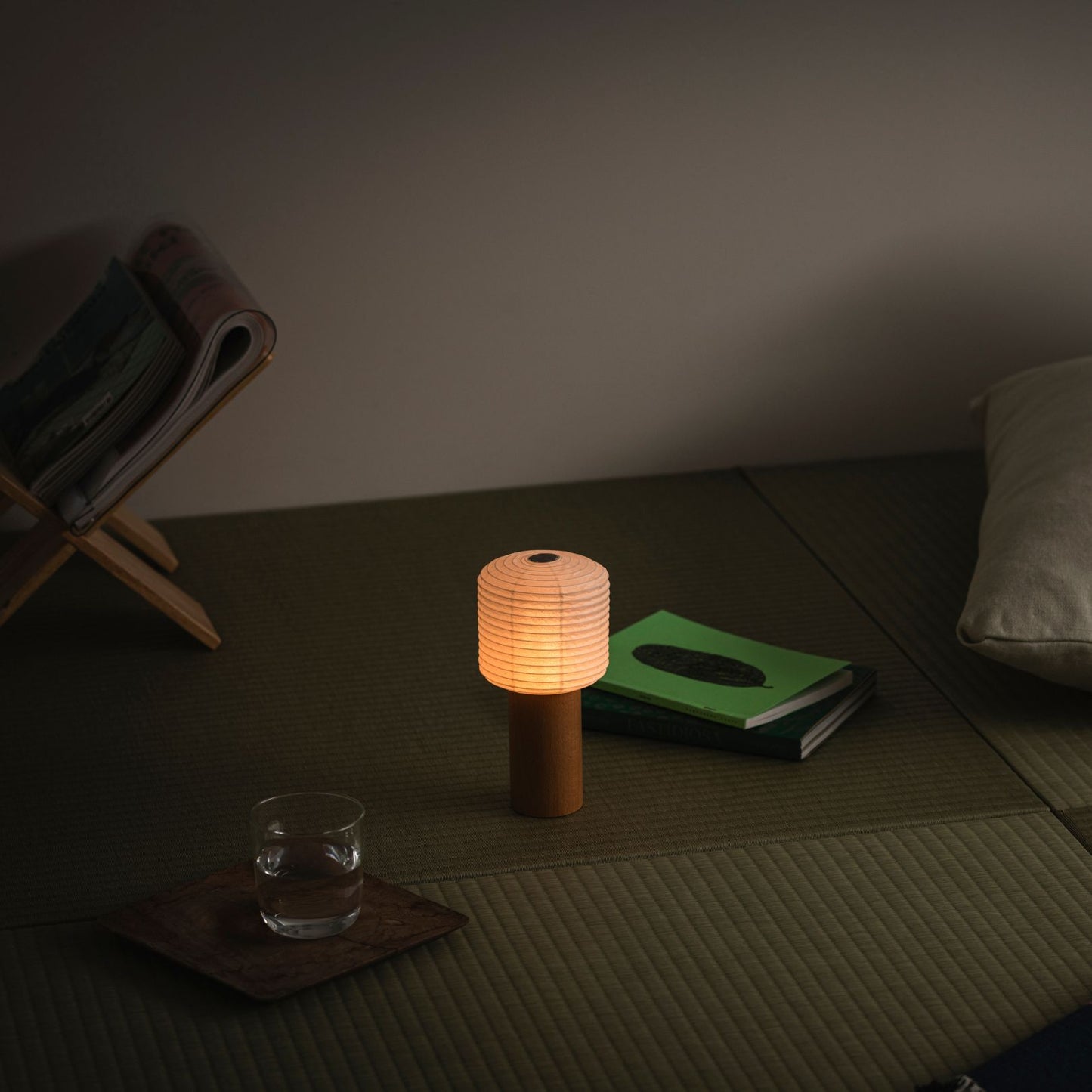 Eine tragbare Papier-Tischlampe, die warm leuchtet und auf einer traditionellen japanischen Tatami-Matte platziert ist