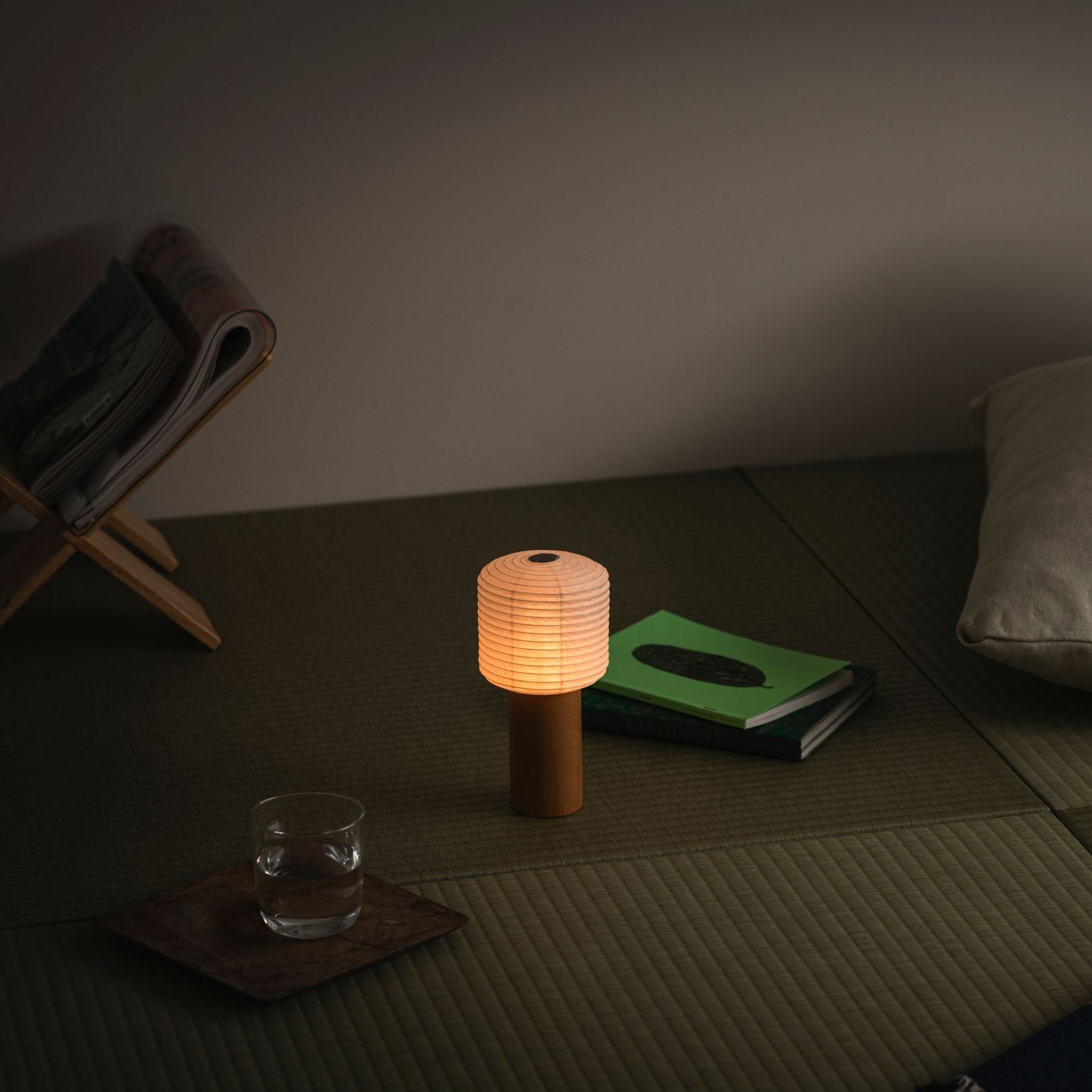 Eine tragbare Papier-Tischlampe, die warm leuchtet und auf einer traditionellen japanischen Tatami-Matte platziert ist