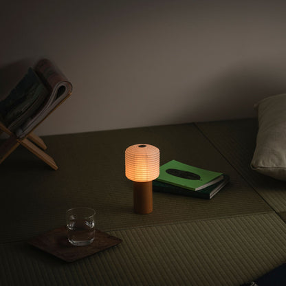Eine tragbare Papier-Tischlampe, die warm leuchtet und auf einer traditionellen japanischen Tatami-Matte platziert ist
