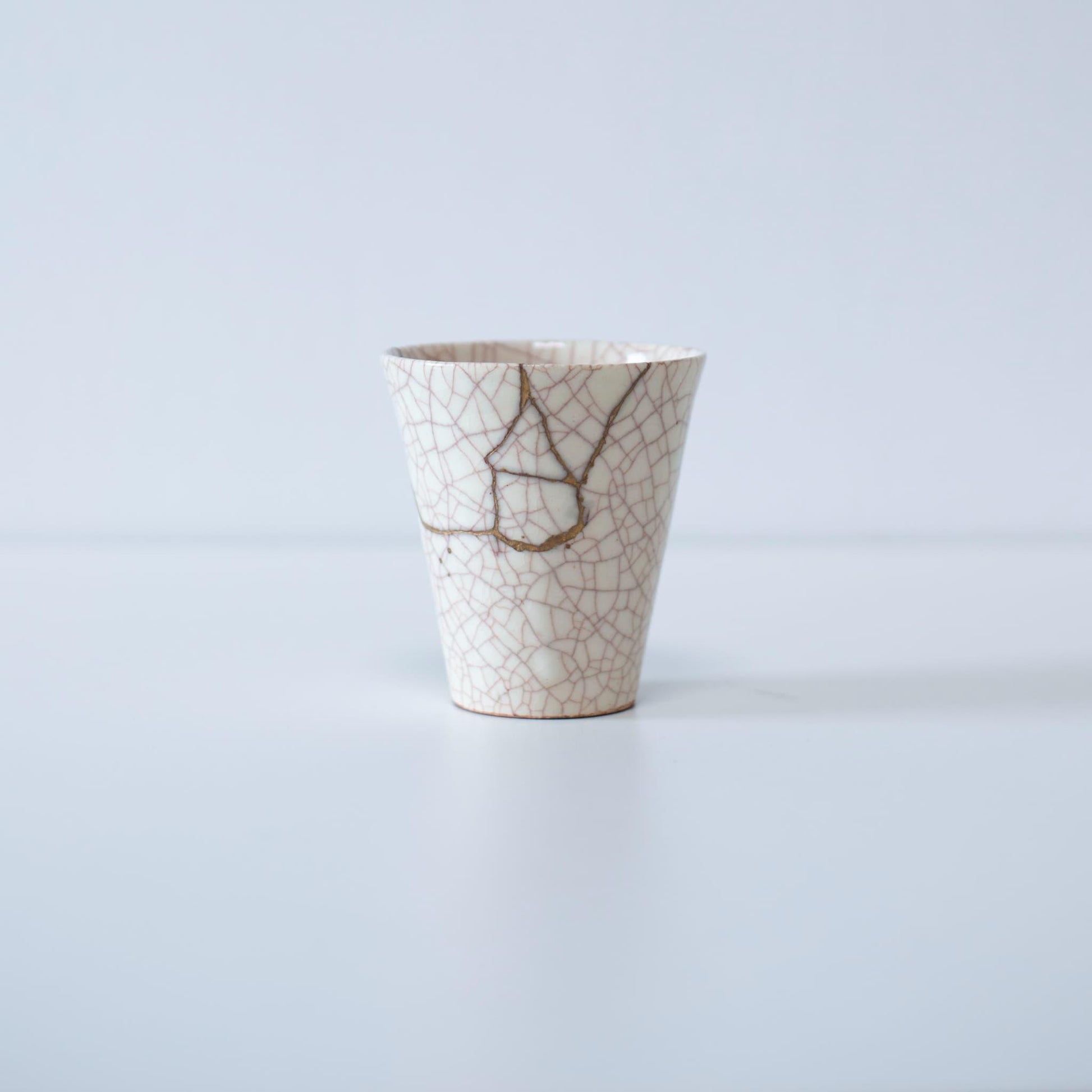 hvid keramisk kop elegant repareret med kintsugi-teknikken, der viser skønheden ved uperfekthed og reparationens kunst.