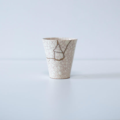 hvid keramisk kop elegant repareret med kintsugi-teknikken, der viser skønheden ved uperfekthed og reparationens kunst.