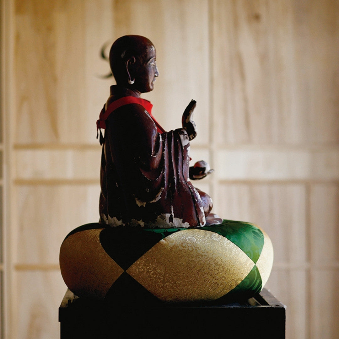 Buddha-statue siddende på Sakae Kinran meditationspude, traditionelt tempeldesign