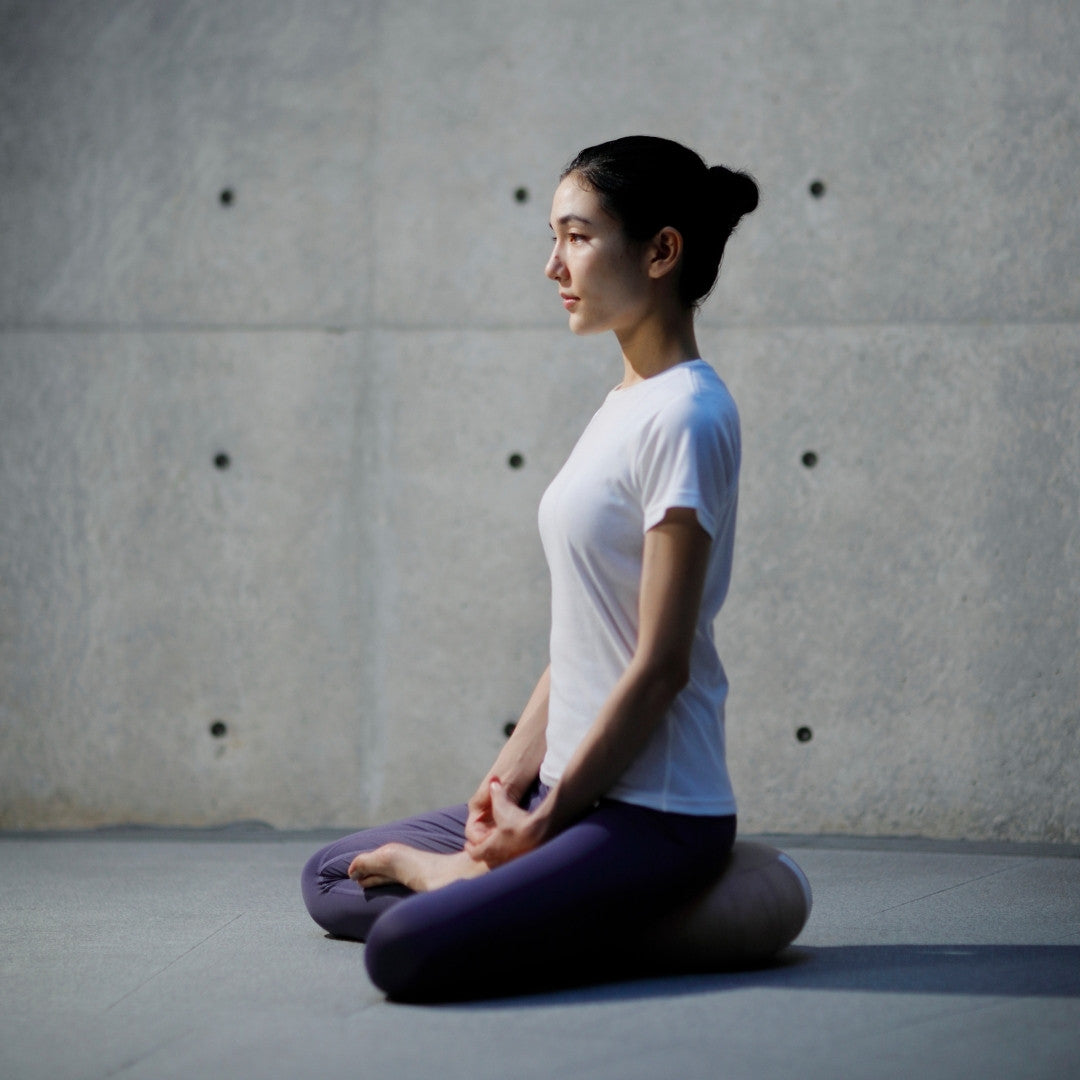 kvinde siddende i lotusstilling og mediterende med en japansk meditationspude Zafu