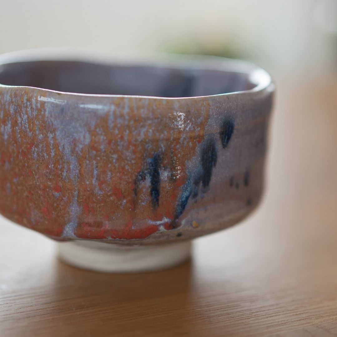 "Nærbillede, der viser den dramatiske Navy og Rød Splash-glasur på den håndlavede matcha chawan, med fokus på teksturen og den lyse lilla Kinyo-glasurbase fra Shinzan Kiln."