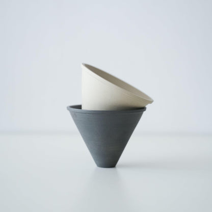 A stack of minimalist black and white Banko ware coffee drippers.